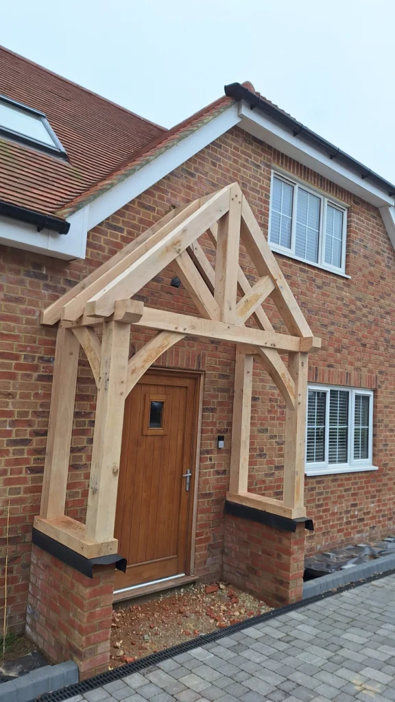 Professional installation of a traditional oak-framed porch kit in Battle, featuring structural timber beams and a pitched roof.