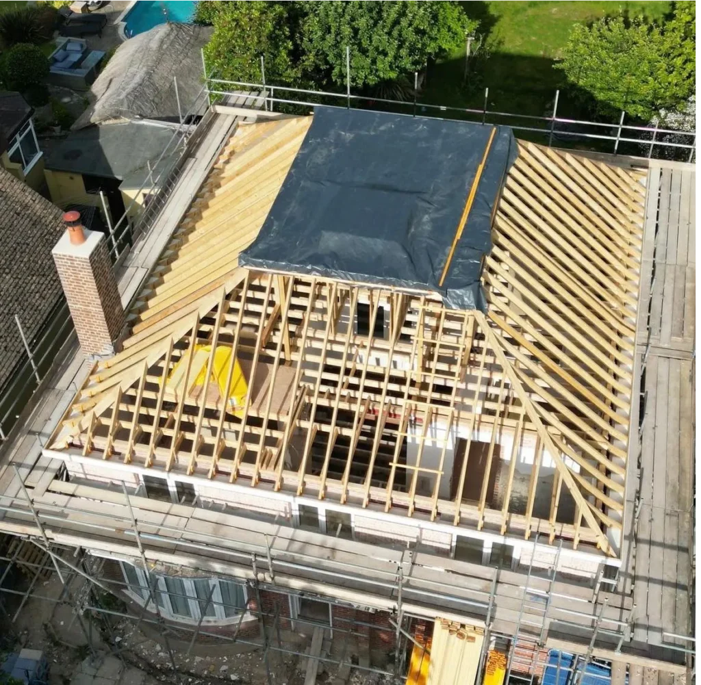 Aerial drone view showing a complex traditional cut-and-pitch roof carcass under construction, with detailed timber rafters and extensive site scaffolding in Hastings, East Sussex.