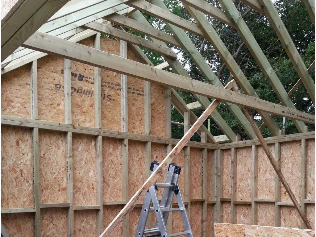 Interior view showing the precision structural timber framing, OSB wall sheathing, and vaulted ceiling rafters.