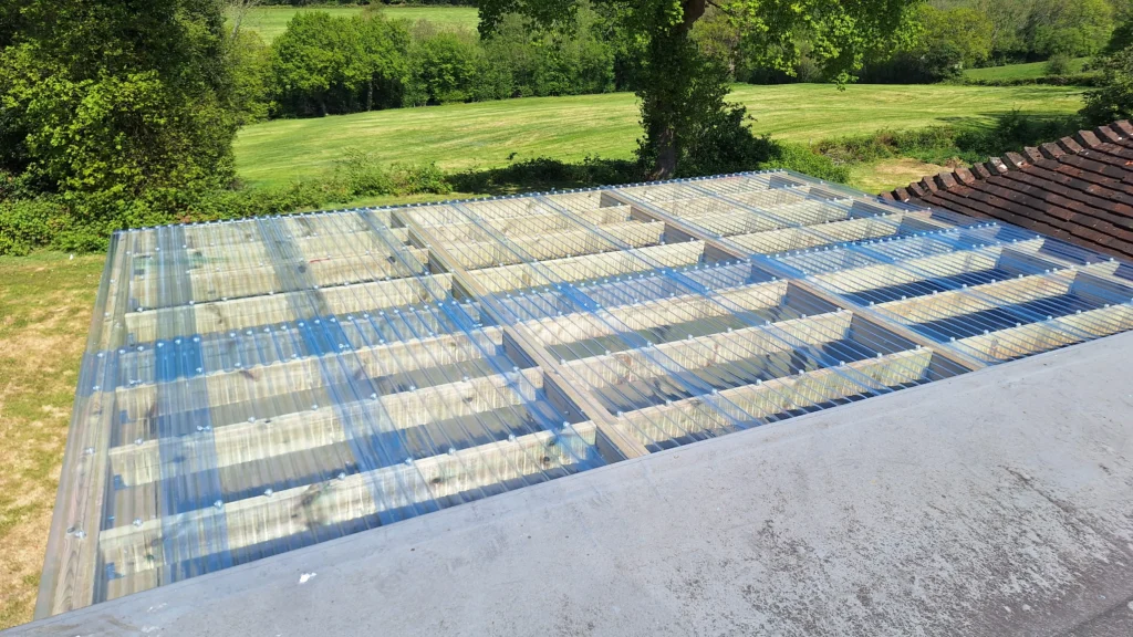 An elevated view of the pergola roof showing the pitch and drainage fall of the clear corrugated plastic sheets over the 6x2 timber rafters.