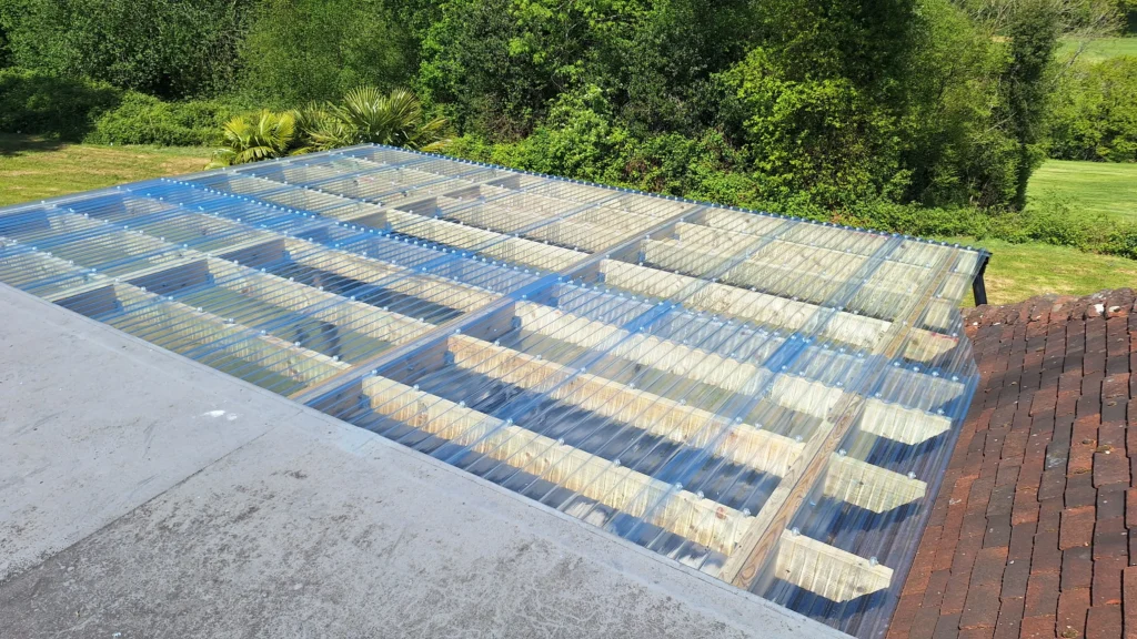 A top-down view of the pergola roof construction, featuring a 6x2 timber frame covered with clear corrugated plastic roofing for weather protection.
