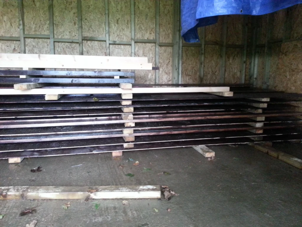 Close-up of the high-quality dark-stained timber weatherboarding stacked and ready for installation.